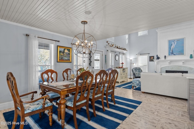 dining area featuring ornamental molding, wood finished floors, a fireplace, baseboards, and a chandelier