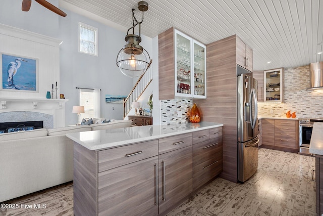 kitchen with decorative backsplash, appliances with stainless steel finishes, a peninsula, and wall chimney range hood