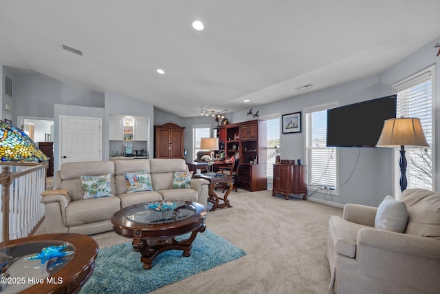 living room featuring lofted ceiling, a healthy amount of sunlight, visible vents, and light carpet