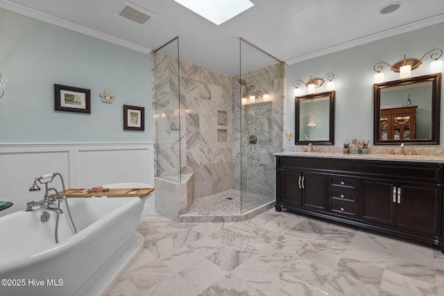 full bathroom with a skylight, marble finish floor, a freestanding bath, and a sink