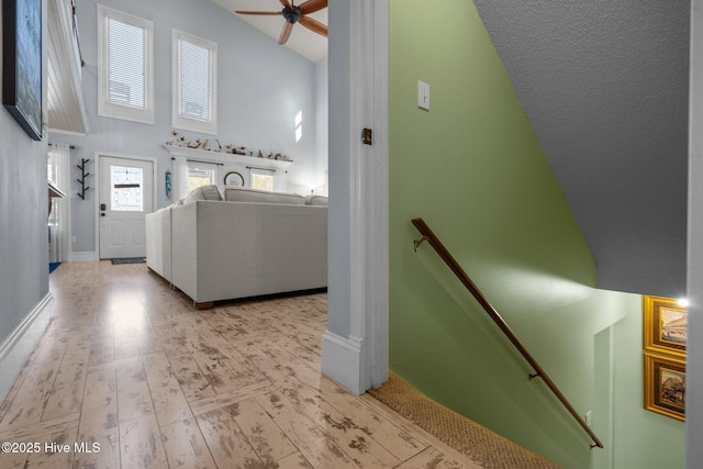 washroom with baseboards, a high ceiling, hardwood / wood-style floors, and a ceiling fan