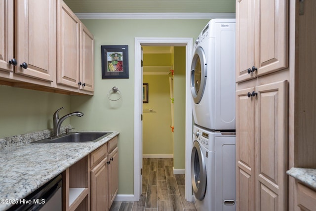 laundry area with crown molding, baseboards, wood tiled floor, stacked washer and dryer, and a sink