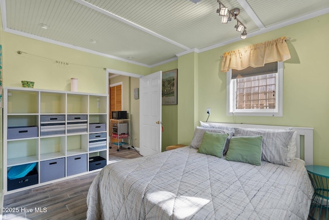 bedroom featuring dark wood-style floors, rail lighting, and crown molding