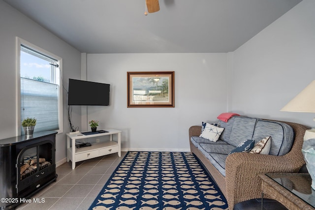 living area with baseboards, dark tile patterned flooring, and ceiling fan