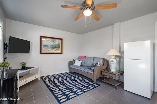 living area featuring baseboards, dark tile patterned flooring, and ceiling fan