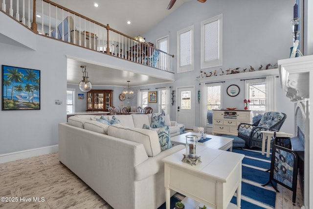 living room with ceiling fan with notable chandelier, recessed lighting, baseboards, and high vaulted ceiling