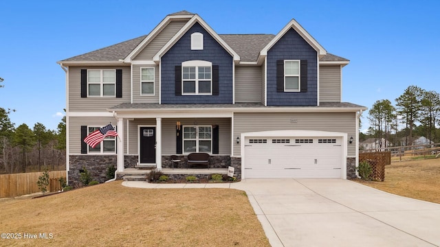 craftsman-style house featuring fence, a porch, a front yard, stone siding, and driveway