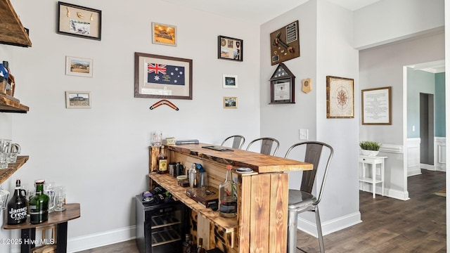 dining area featuring bar, baseboards, and dark wood-style flooring