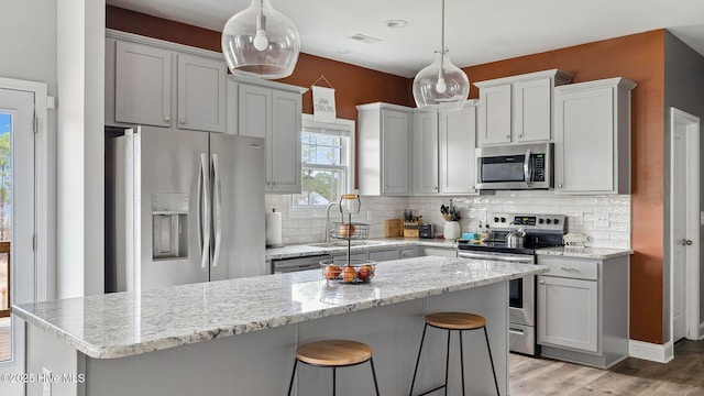 kitchen with visible vents, light wood-style flooring, a sink, tasteful backsplash, and stainless steel appliances