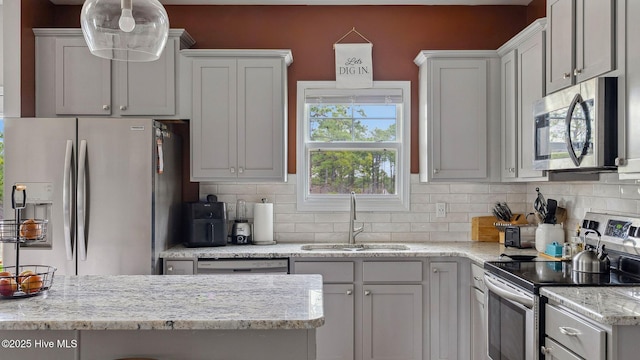 kitchen featuring a sink, stainless steel appliances, light stone counters, and decorative backsplash