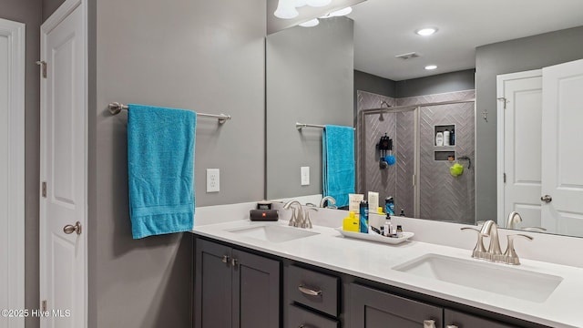 full bathroom with a shower stall, double vanity, visible vents, and a sink