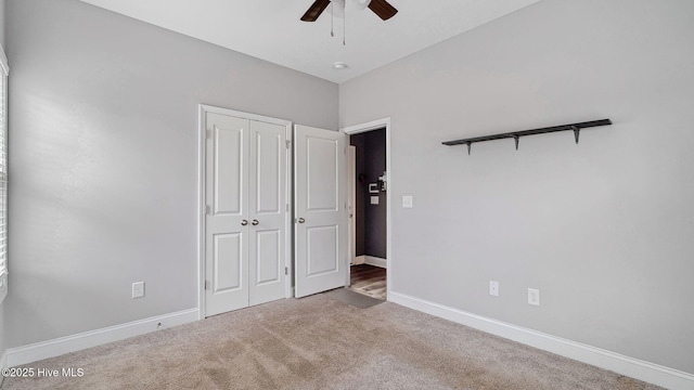 unfurnished bedroom with a closet, carpet flooring, a ceiling fan, and baseboards