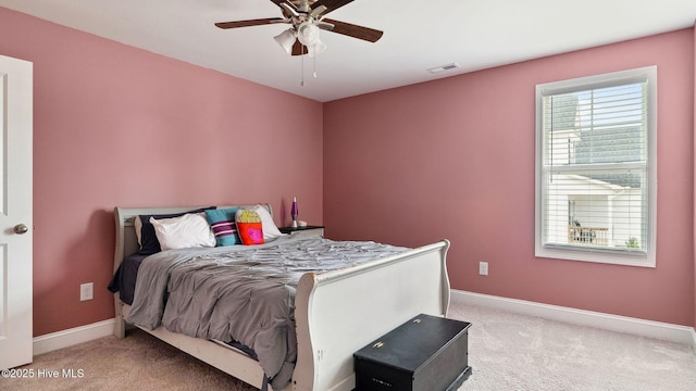 bedroom with visible vents, light colored carpet, baseboards, and ceiling fan