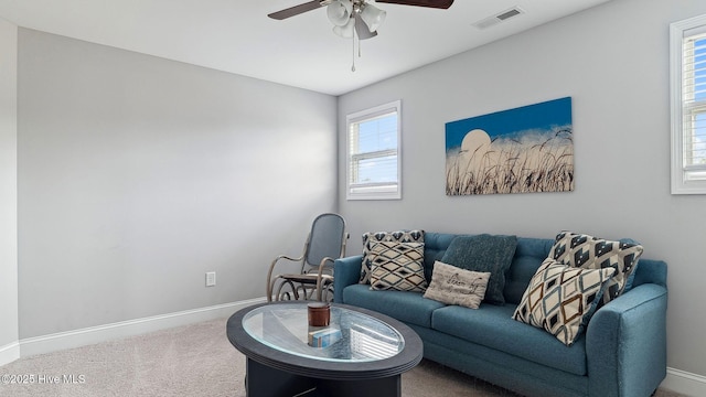 living area with visible vents, baseboards, carpet, and a ceiling fan