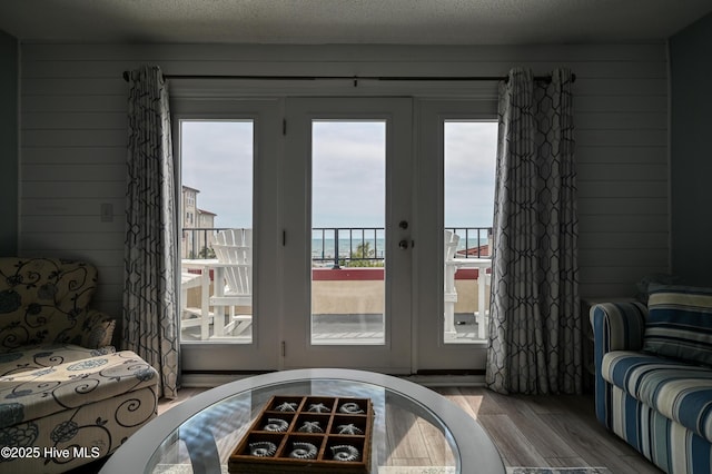 doorway featuring wooden walls, a textured ceiling, and wood finished floors