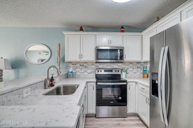 kitchen with a sink, tasteful backsplash, appliances with stainless steel finishes, and white cabinetry