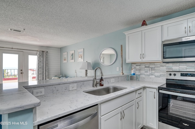 kitchen featuring tasteful backsplash, open floor plan, white cabinets, stainless steel appliances, and a sink