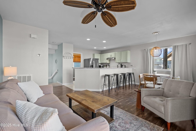 living room with visible vents, baseboards, a ceiling fan, and dark wood-style flooring