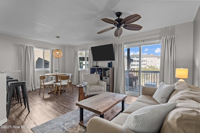 living area featuring light wood-type flooring, baseboards, and ceiling fan