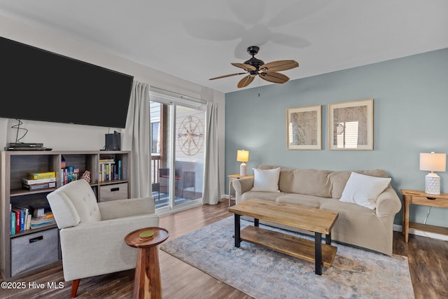 living area with wood finished floors, a ceiling fan, and baseboards