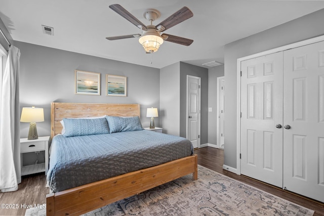 bedroom featuring wood finished floors, visible vents, a ceiling fan, a closet, and baseboards