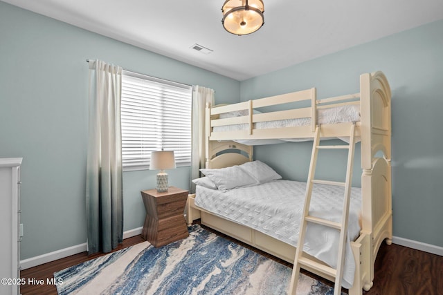 bedroom with wood finished floors, visible vents, and baseboards