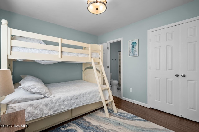 bedroom with wood finished floors, baseboards, and a closet