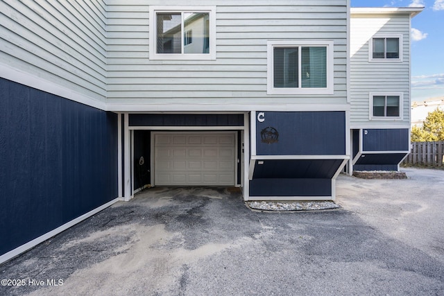 garage featuring aphalt driveway and fence