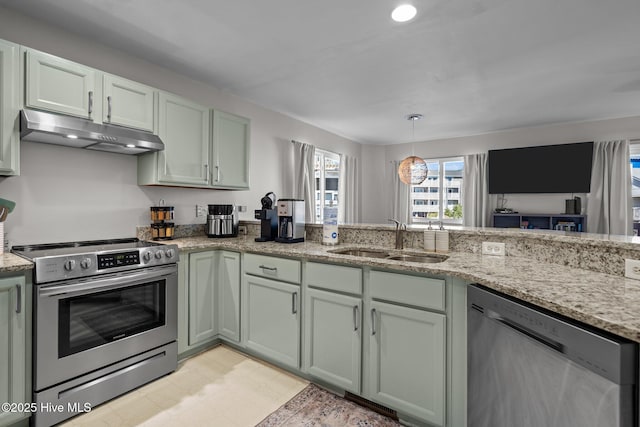 kitchen with light stone counters, light floors, under cabinet range hood, stainless steel appliances, and a sink