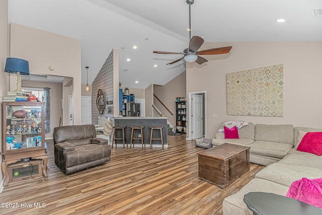 living area with stairway, recessed lighting, light wood-style flooring, high vaulted ceiling, and a ceiling fan