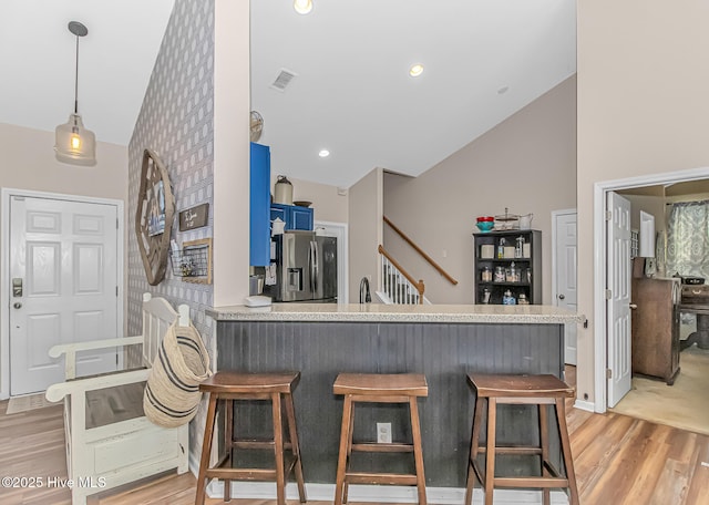 kitchen featuring light wood-style flooring, a kitchen breakfast bar, blue cabinets, and stainless steel refrigerator with ice dispenser