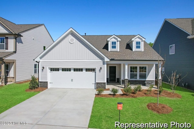 craftsman house with board and batten siding, a front lawn, concrete driveway, stone siding, and an attached garage