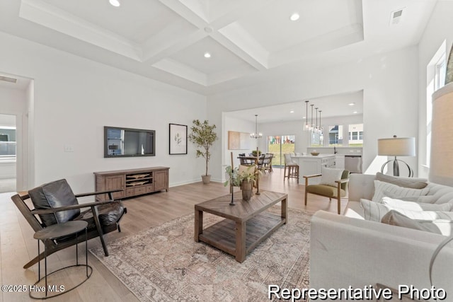 living room with visible vents, coffered ceiling, light wood-style flooring, beamed ceiling, and a notable chandelier