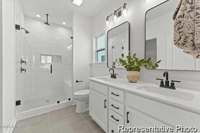 full bathroom with double vanity, a stall shower, toilet, and a sink