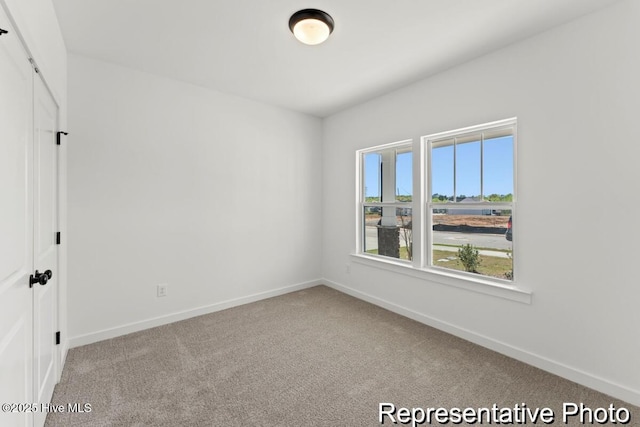 carpeted spare room featuring baseboards