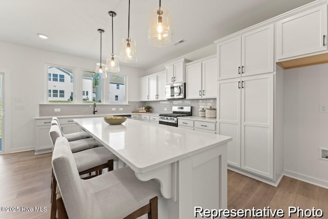 kitchen with stainless steel appliances, backsplash, visible vents, and white cabinetry