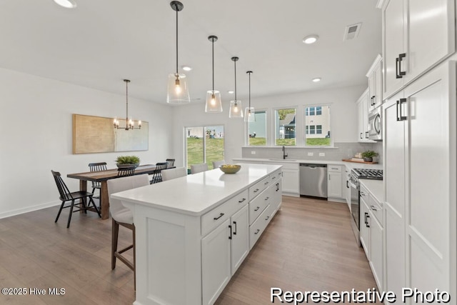 kitchen featuring white cabinetry, appliances with stainless steel finishes, a breakfast bar area, and light countertops