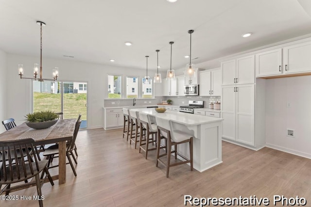 kitchen featuring appliances with stainless steel finishes, white cabinets, a center island, and light countertops