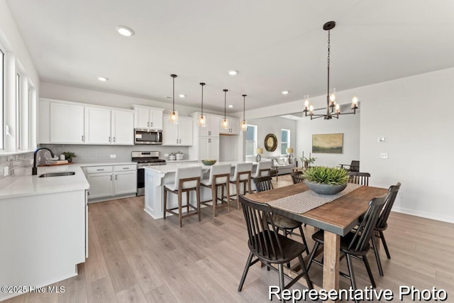 dining space featuring a notable chandelier, recessed lighting, light wood-type flooring, and baseboards