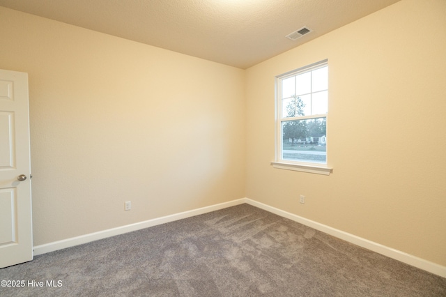 empty room with visible vents, baseboards, carpet, and a textured ceiling