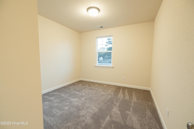 carpeted empty room featuring visible vents, a textured ceiling, and baseboards