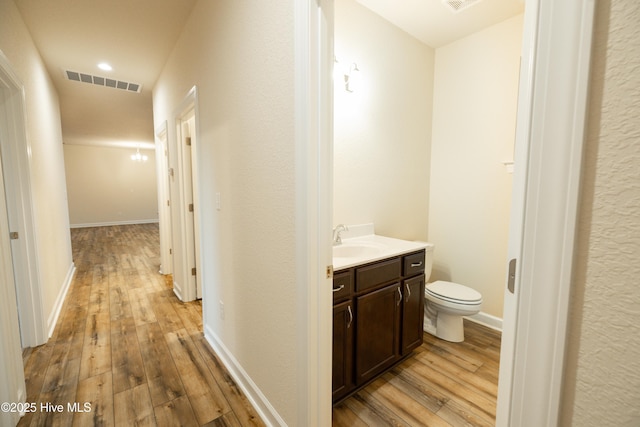 bathroom with visible vents, toilet, hardwood / wood-style floors, baseboards, and vanity