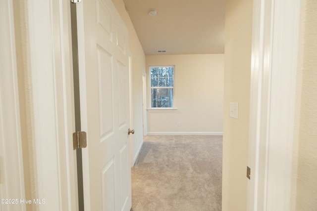 corridor with carpet, visible vents, and baseboards