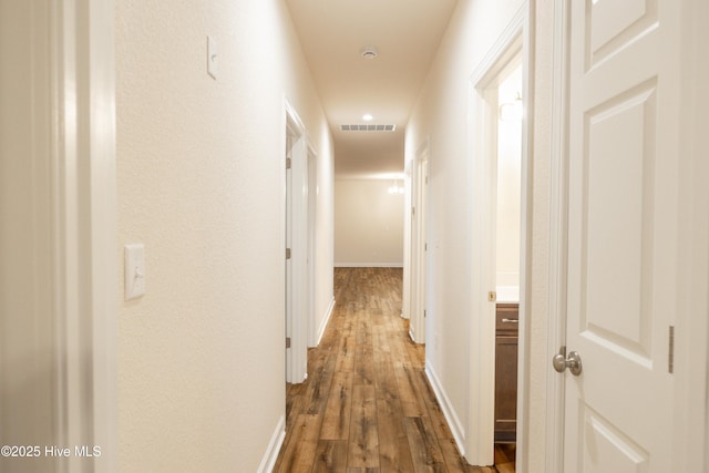 corridor with visible vents, baseboards, and wood finished floors