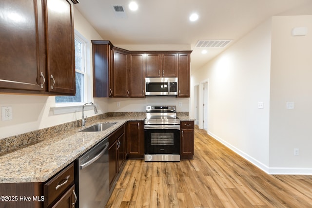 kitchen with dark brown cabinetry, recessed lighting, light wood-style flooring, stainless steel appliances, and a sink