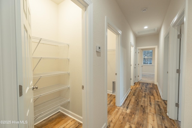 hall featuring recessed lighting, attic access, baseboards, and hardwood / wood-style flooring