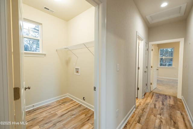 clothes washing area with visible vents, hookup for a washing machine, attic access, and light wood-style floors