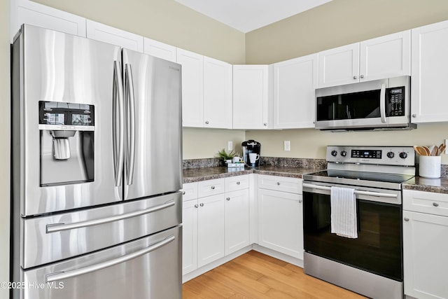 kitchen featuring dark countertops, appliances with stainless steel finishes, white cabinetry, and light wood-style floors