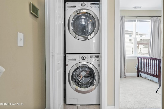 clothes washing area featuring carpet, baseboards, visible vents, laundry area, and stacked washer and clothes dryer