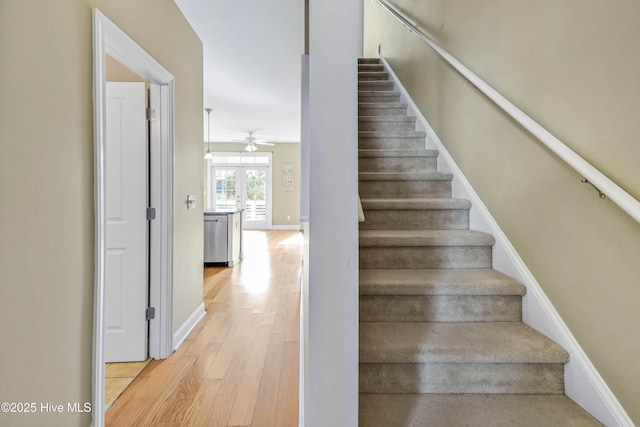 stairs featuring a ceiling fan, wood finished floors, and baseboards